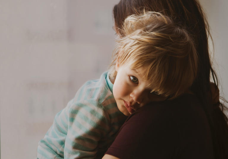 a blond baby in the arms of their mother