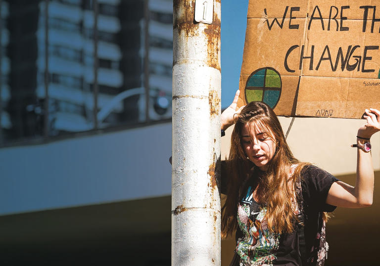 Image of a young woman holding banner at a protest