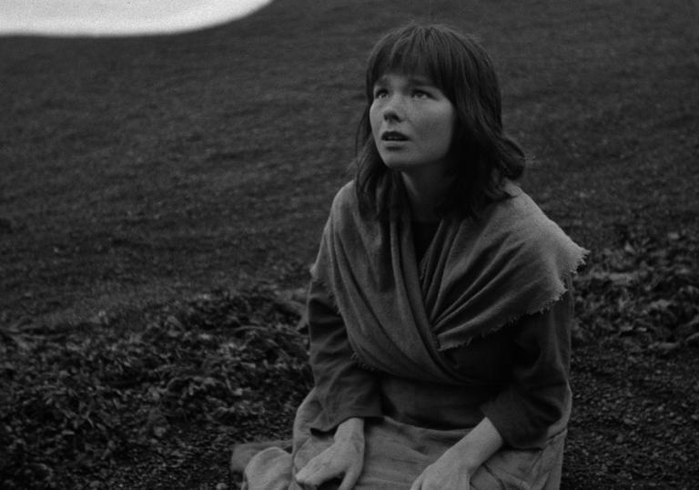 A black and white image of young Bjork kneeling on the ground looking up