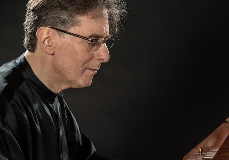 Robert Levin playing the piano, wearing a flowing black silk shirt 