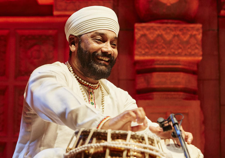 Sukhwinder Sing playing tabla and smiling at the audience