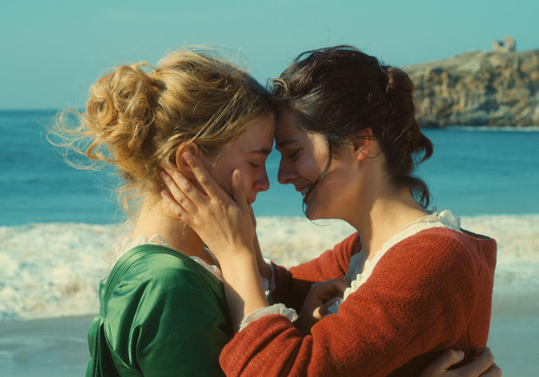 Two women embrace on a windswept beach