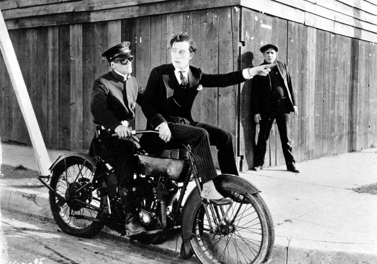 buster keaton sitting on the front of a motorbike