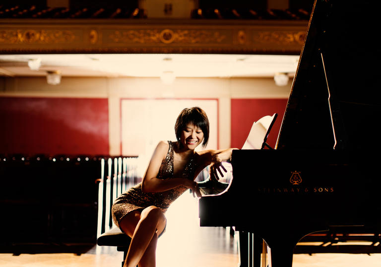 An playful image of Yuja sitting at her piano, facing the camera 