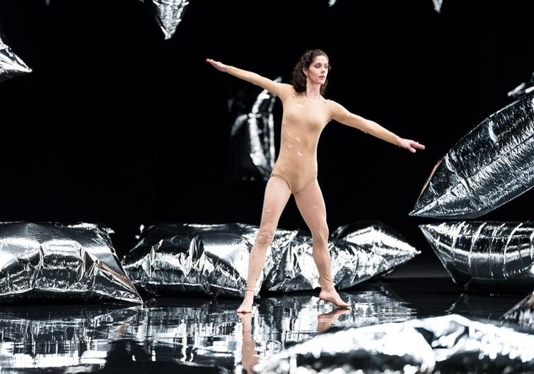 A woman dancing amongst silver cushions