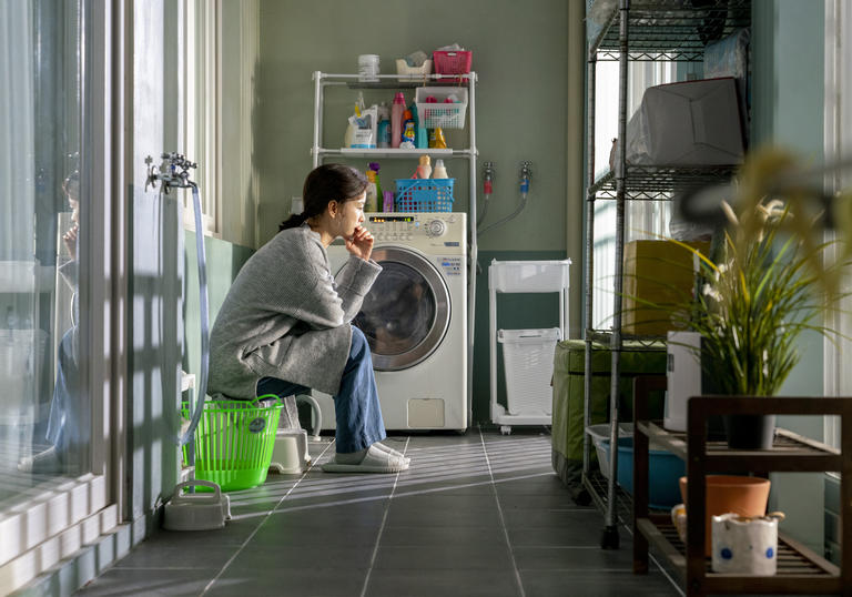 woman sitting in her utility room in front of the washing machine