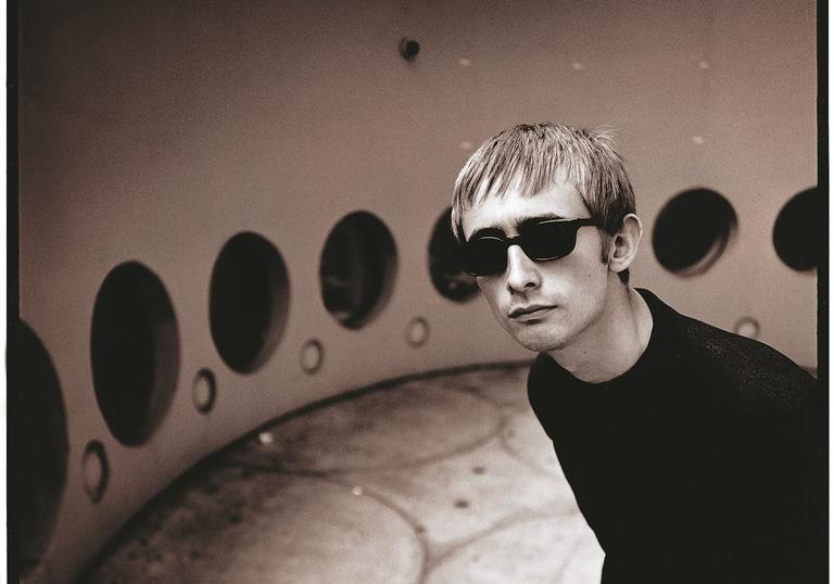 Black and white photo of Neil Hannon in a retrofuturistic room with black circular windows