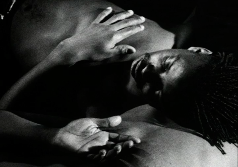 A young man lies down in a restful pose in black and white