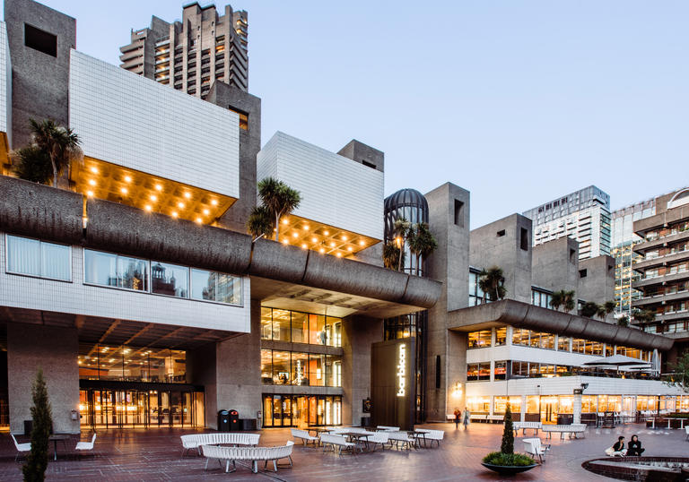 Image of the Barbican Lakeside terrace in early evening with lights glowing