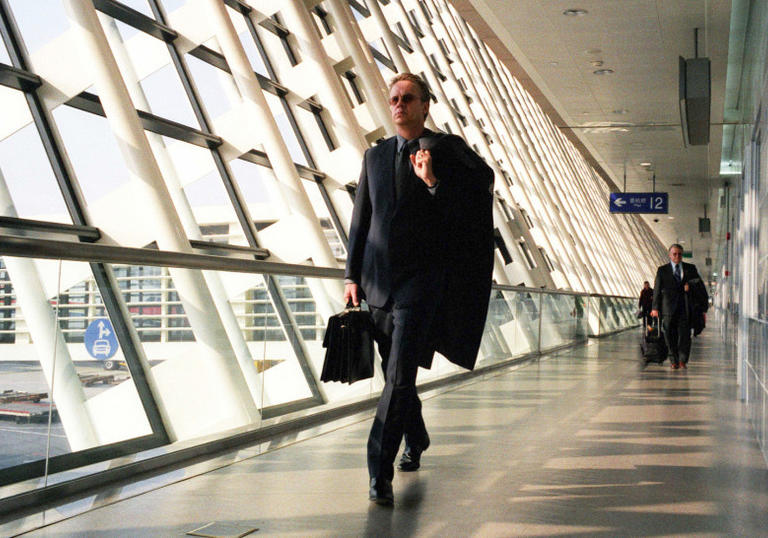 Man walking down a glass corridor