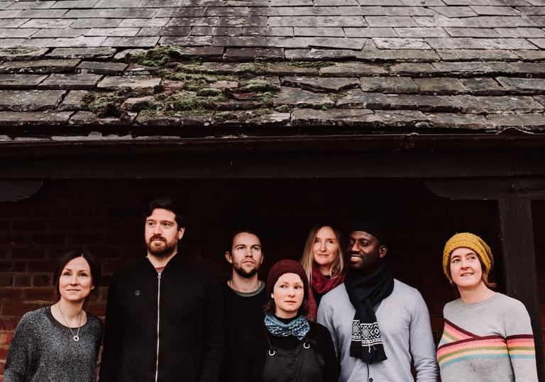 The performers from The Lost Words stand outside a house with a slated roof