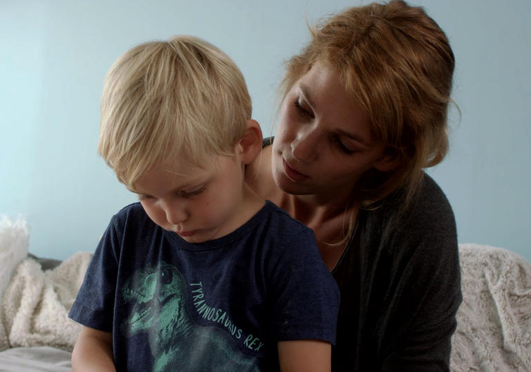 child sitting on woman's lap looking downwards