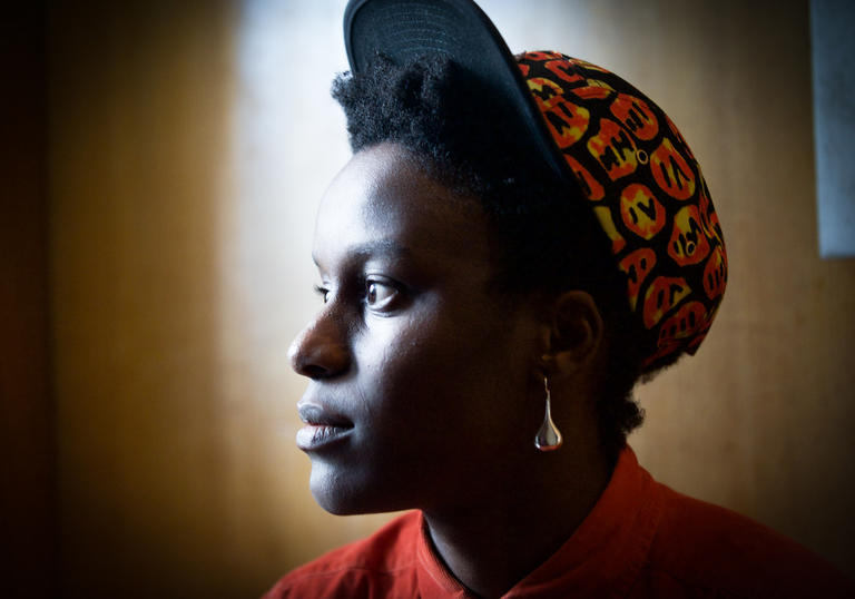 An image of a persons face looking awy from the camera to the left, and wearing a baseball cap