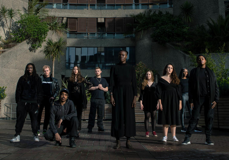 10 Guildhall PACE students dressed in black standing in sunshine on Barbican estate