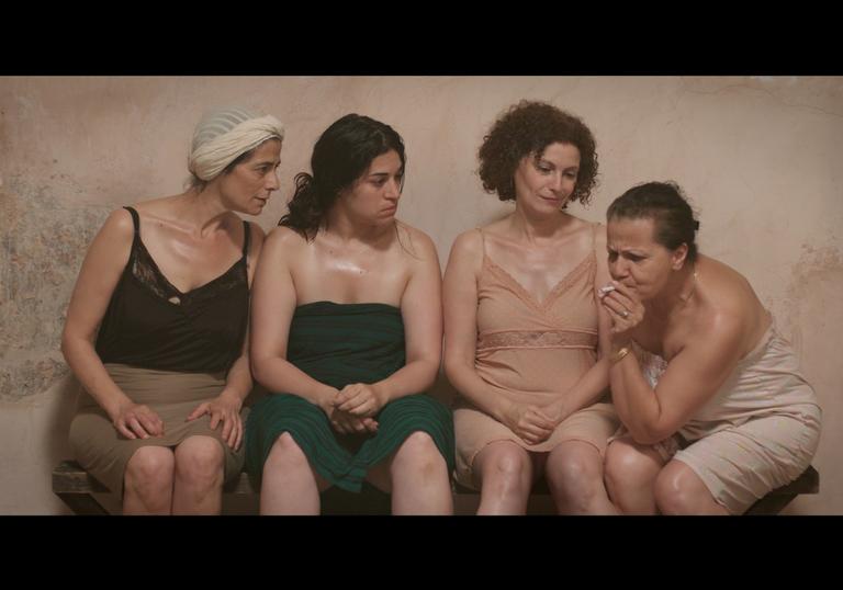a group of women are in a bathing house together, talking