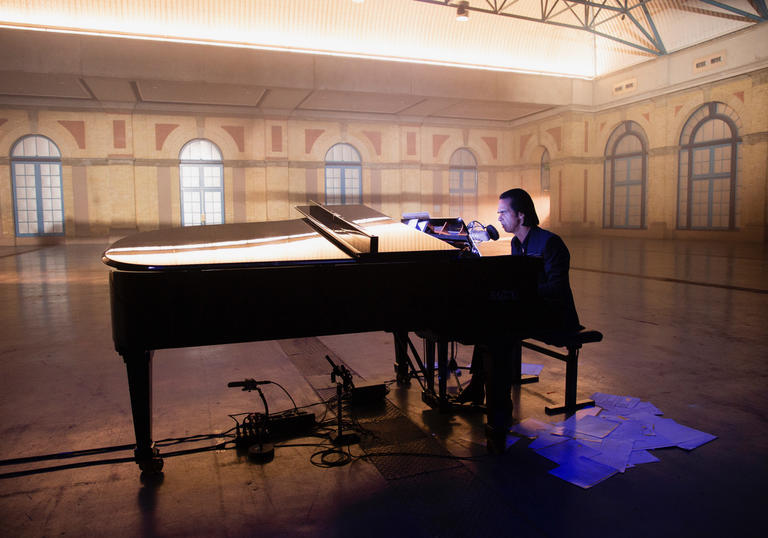 Nick Cave sitting at the piano in Alexandra Palace