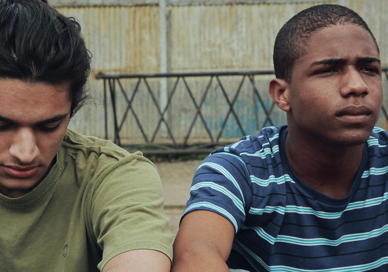 Two young men sitting next to each other on some steps