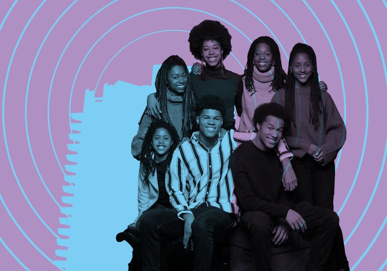 The Kanneh-Mason Family smiling with the Barbican tower illuminated on them