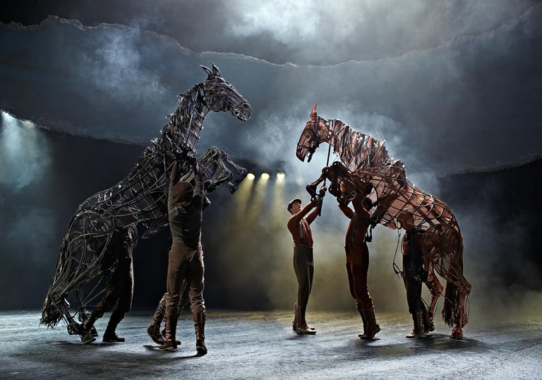 puppet horses rearing on their hind legs whilst men are trying to control them