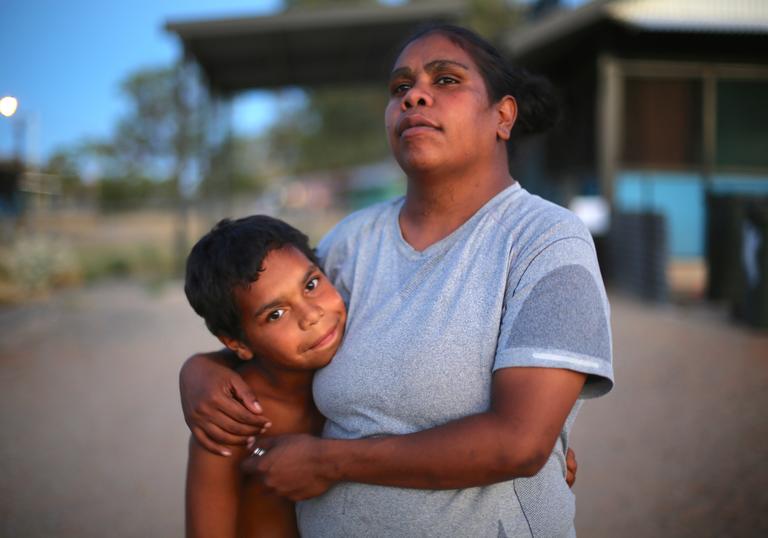 a mother and son stand embracing 