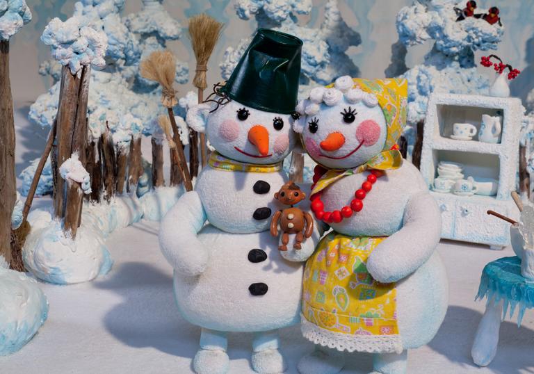 A snow man and snow woman hold a snow baby