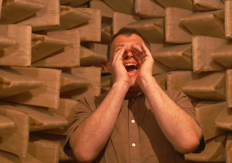 A man shouts through his cupped hands in In A Silent Way