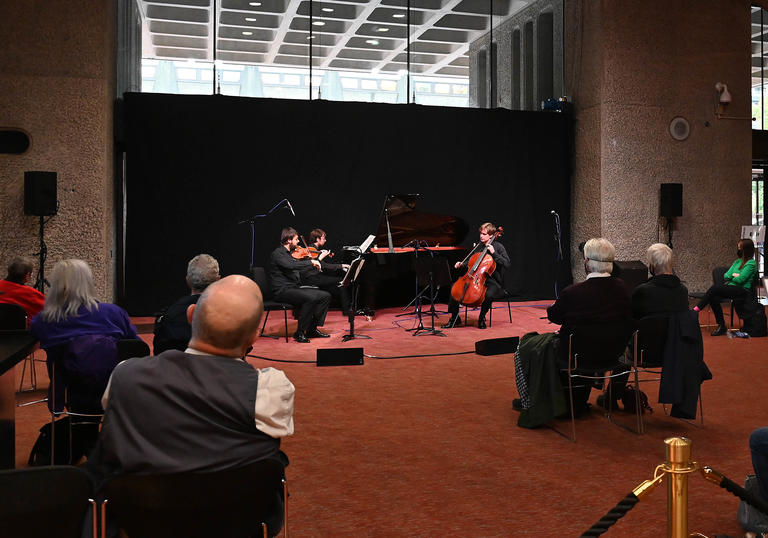 Audiences enjoying a socially distanced performance by the Mithras Trio on Barbican Level G