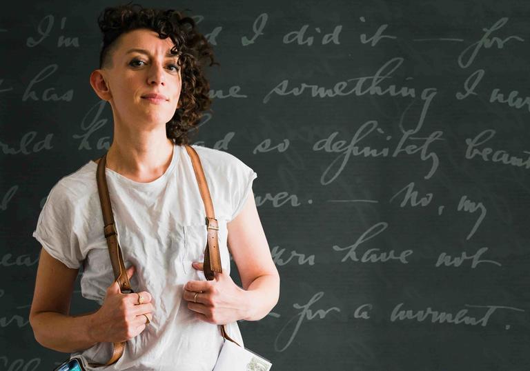 Person standing against a blackboard wearing braces. 