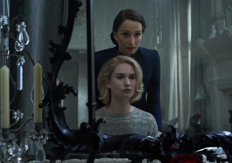 Lily James (playing Rebecca) looking into a mirror with Kristen Scott Thomas standing over her