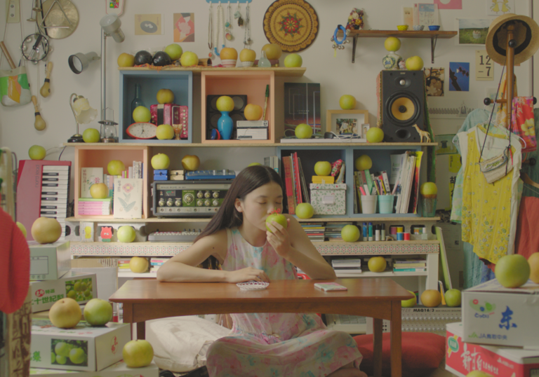 a young girl eats a pear at her desk surrounded by pears
