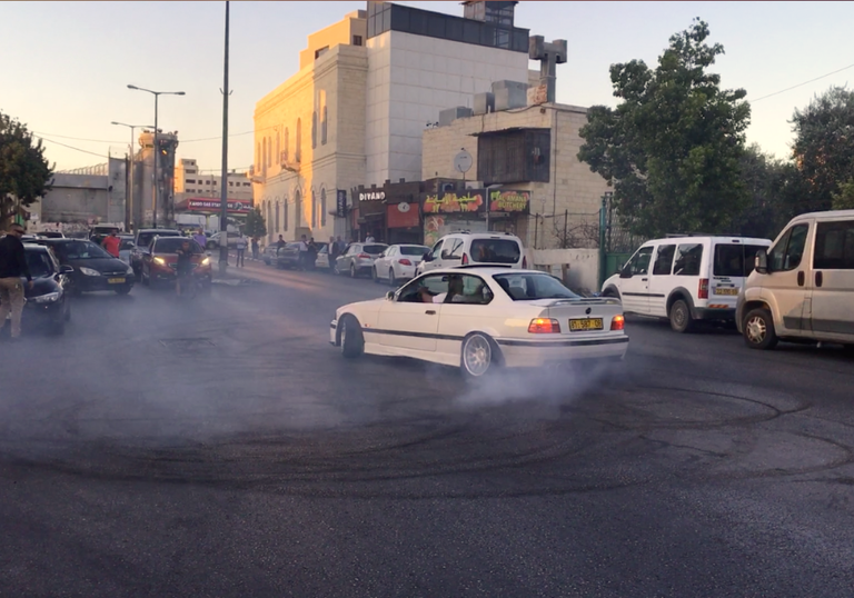 A white car skids on a road busy with other cars