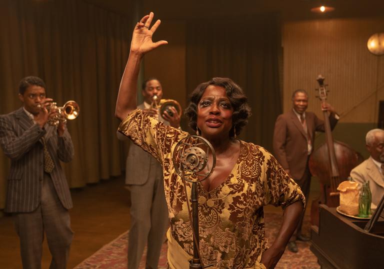 Viola Davis plays Ma Rainey singing into a mic with her band around her