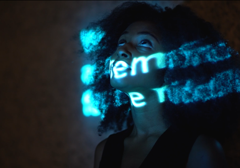 A projection of words in blue writing has been projected onto a persons face