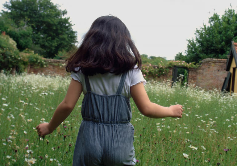 Girl running through field of grass