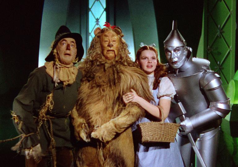 Dorothy, the lion, the tin man and the scarecrow cower before the wizard