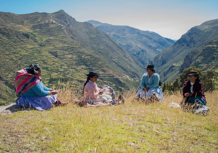 a group of women sit together up in the mountains