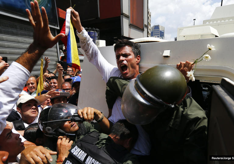 a protestor gets pushed into a police van whilst holding up a flag