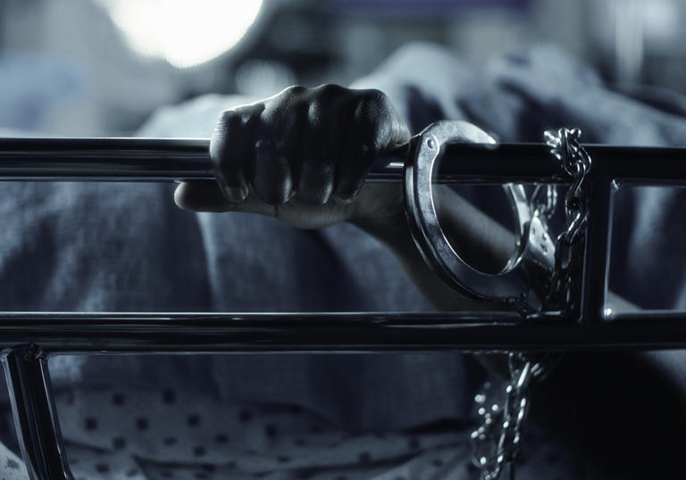 A person's is handcuffed to a hospital bed