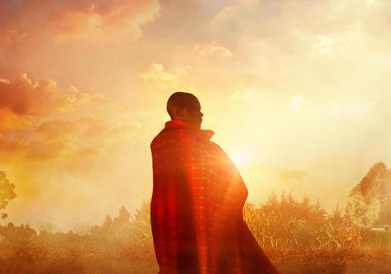 an image of samuel wrapped in a blanket with the sunset behind him