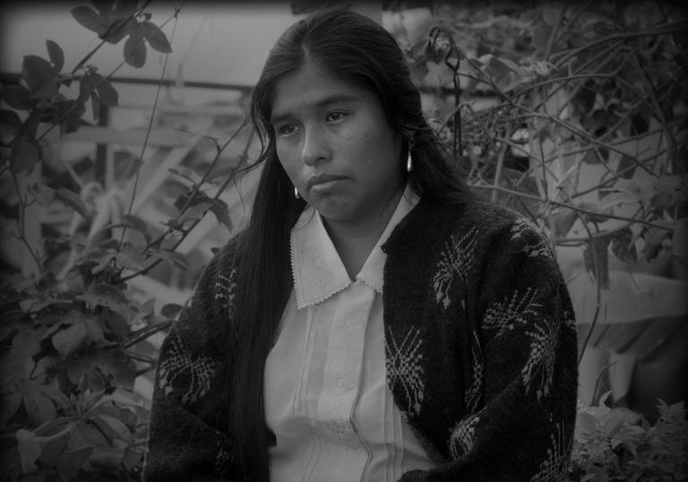 a woman looks forlorn sitting in a garden