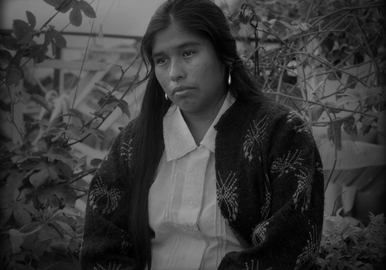 a woman looks forlorn sitting in a garden