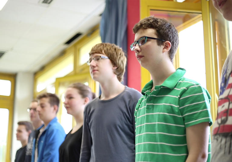 a group of teenagers stand in a line next to each other