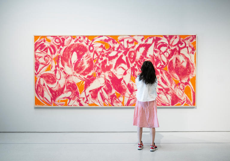 A woman standing in front of a Lee Krasner painting