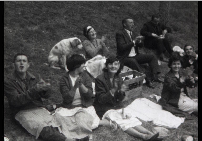 a black and white image of a group of people having a picnic