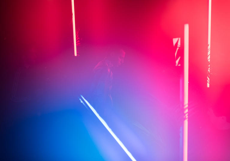 A faint outline of a young man in a neon pink and blue environment