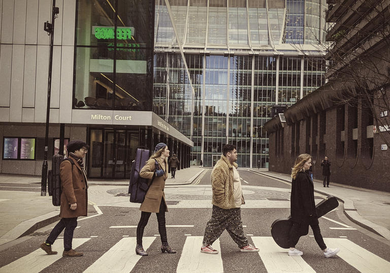 Four Guildhall students on zebra crossing in style of Abbey Road album cover
