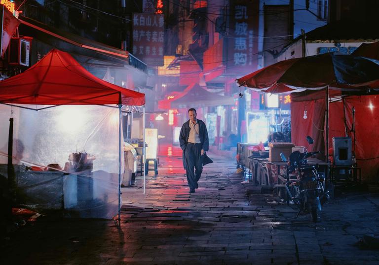 a man walks through the darkly lit streets of a city