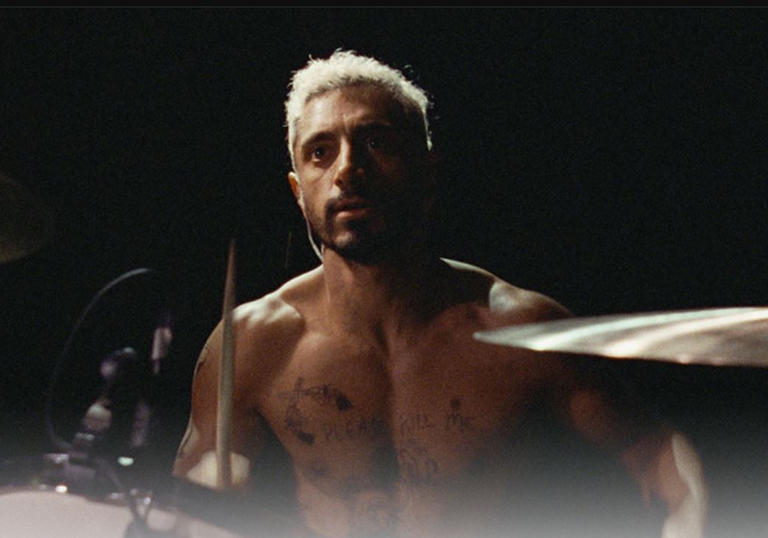 a drummer with bleached blonde hair and no shirt