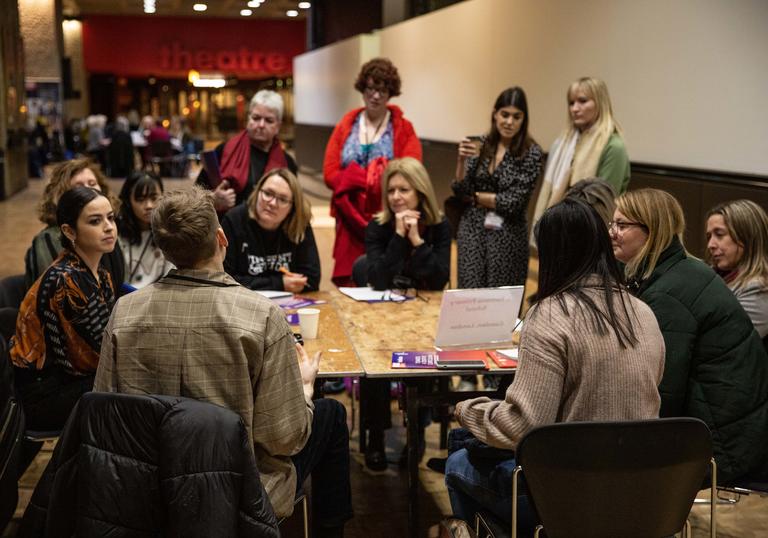 A group of teachers sit around a table in the Barbican centre having a discussion 
