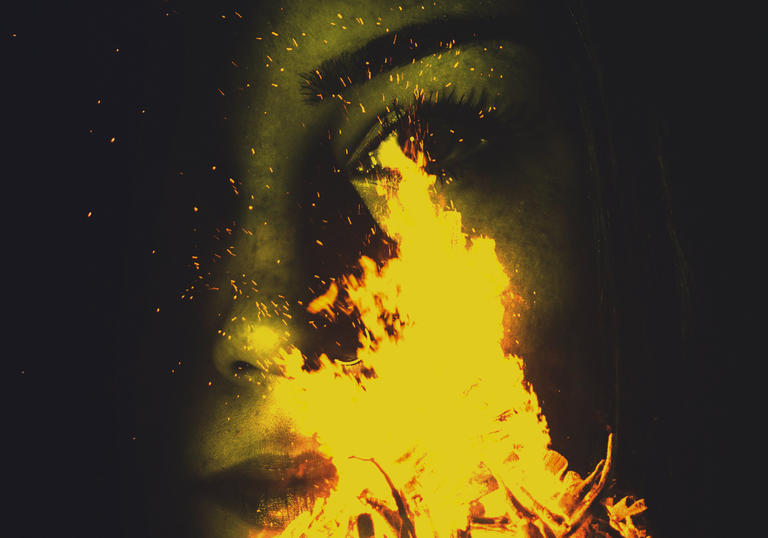 Image of woman's face behind campfire